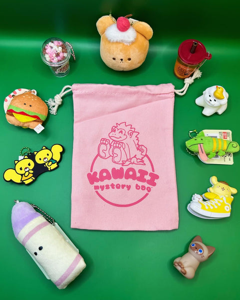 An example of what you might get in a Kawaii mystery bag. It is a pink bag with a pink gorilla logo surrounded by various keychains and gacha. A plush bear head with a strawberry and whipped cream, a fruit tea drink keychain with liquid inside, a figure of a cute bichon dog with a duck on its head, a plush lizard keychain, a clip of Sanrio’s ponponpurin in a yellow sneaker, a brown cat figure, a purple crayon plush keychain, a rubber keychain of Sanrio’s Rorry and Rotti, a plush hamburger keychain, etc