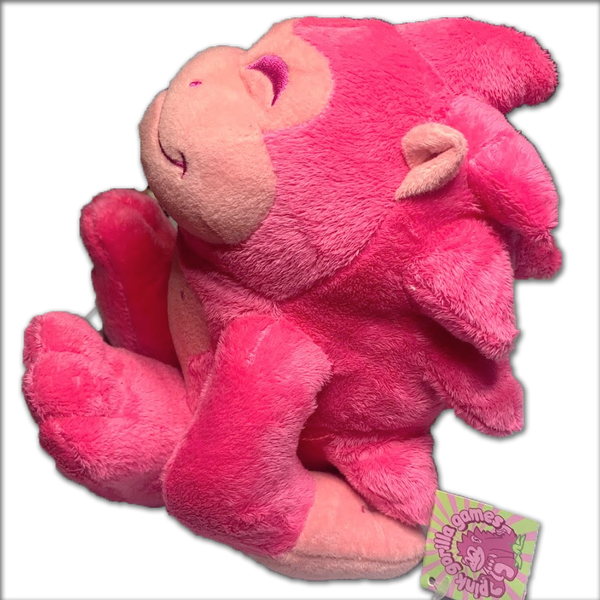 A Pink Gorilla plushie, side view. The plush has bright pink fur with a light pink face, stomach, hands, and toes. Facial features are stitched in bright pink thread.
