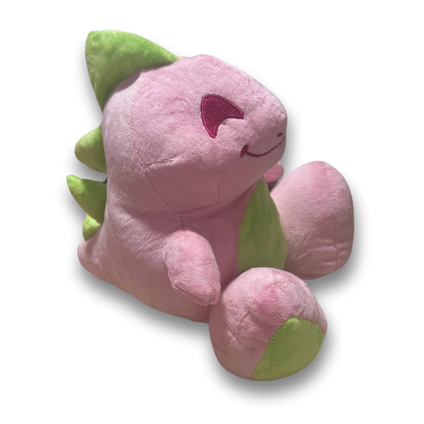 An arial three quarters view of the big pink dinosaur plush. His fur is a fluffy light pink, his spikes and feet are lime green, and his facial details are nicely embroidered.