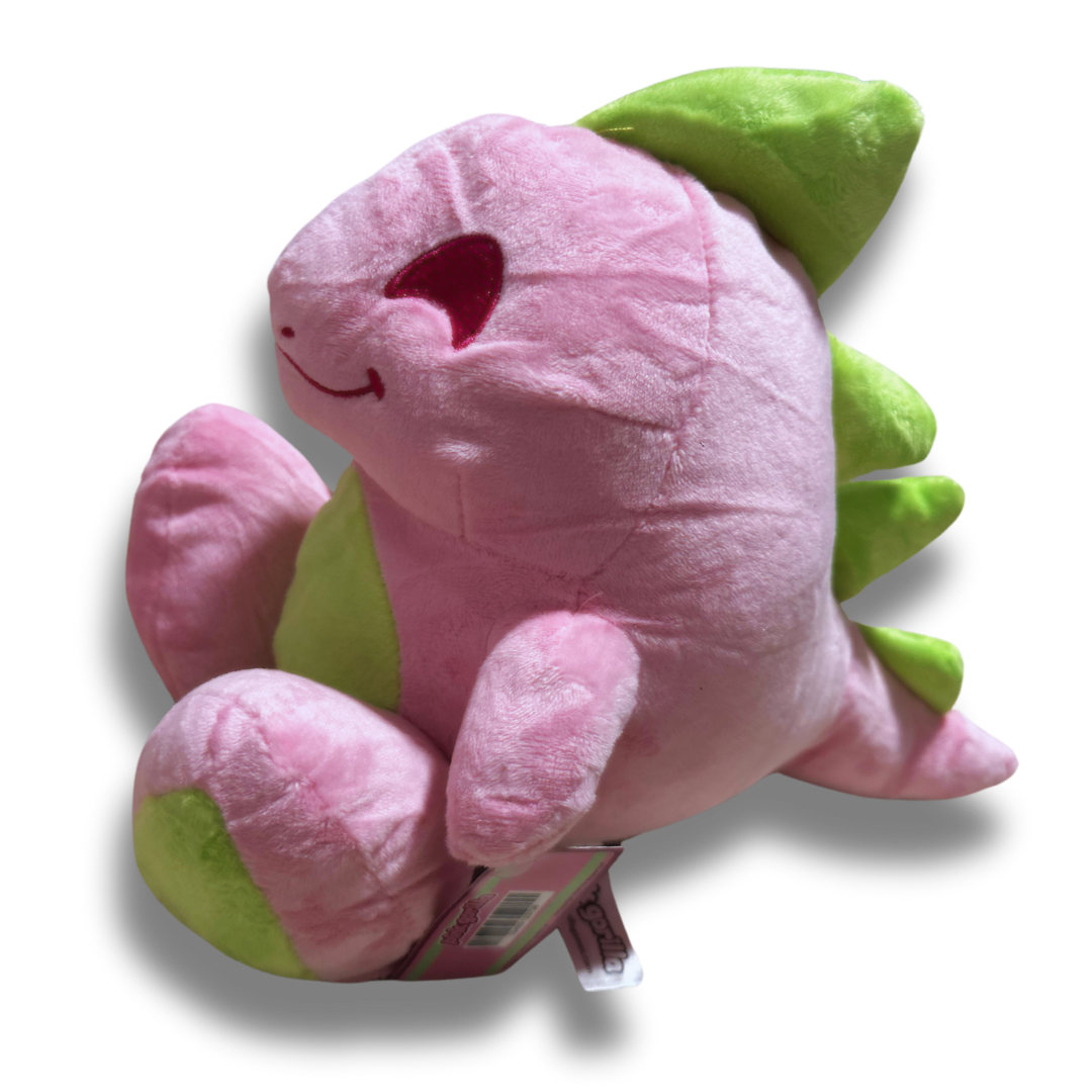 A three quarters view of the large pink dinosaur plush. His fur is a fluffy light pink, his spikes and feet are lime green, and his facial details are nicely embroidered.