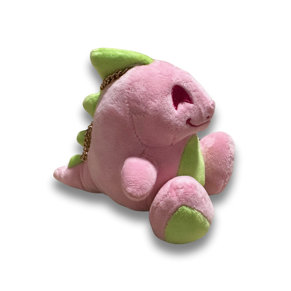 A side view of the small pink dinosaur plush. His fur is a fluffy light pink, his spikes and feet are lime green, and his facial details are nicely embroidered.