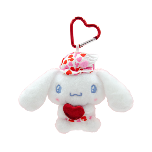 A white Cinnamoroll plush keychain. He is wearing white and red heart-print hat and shirt and is holding a red velvet heart. A red heart-shaped clip is attached to his head.