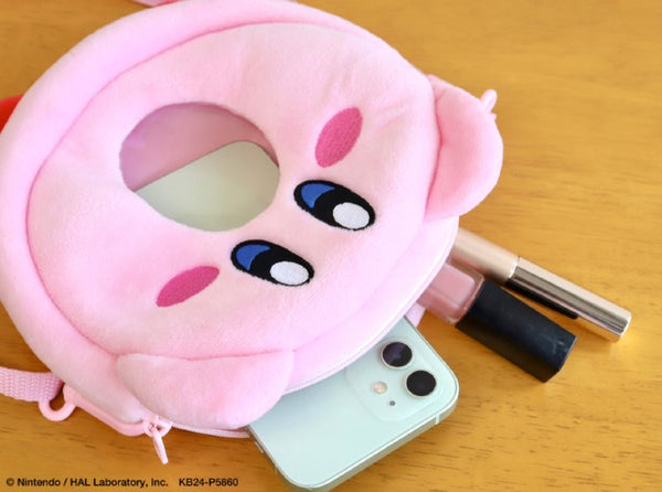 A promotional image from Nintendo/HAL Laboratory of the Kirby plush bag holding an iPhone and makeup, which can be seen through the clear window in the bag.